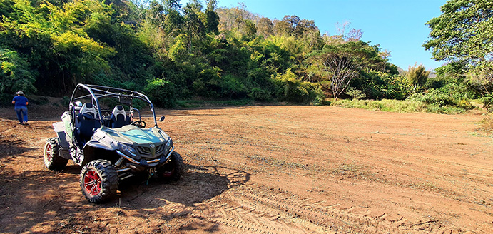 ATV parked on open land with forest behind